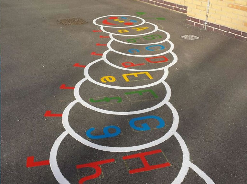 Colorful caterpillar-themed playground markings featuring alphabet letters in bright colors, promoting fun and educational play for children.