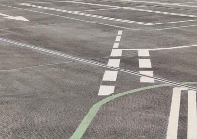Freshly painted parking bays, directional arrows, and green guidance lines in a shopping centre car park, completed by Bournemouth White Lining for professional car park lining services