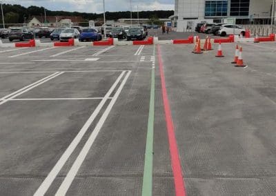 Freshly painted white parking bay lines with red and green guidance lines in a shopping centre car park, completed by Bournemouth White Lining for professional car park lining services