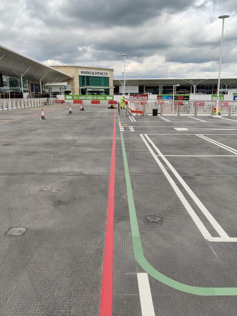 Freshly painted car park lining with red and green lines marking bays and pedestrian walkways at a shopping centre, completed by Bournemouth White Lining for professional car park lining services