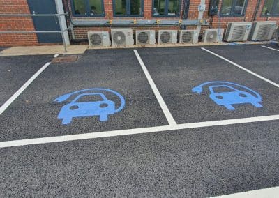 Freshly painted EV charging bay markings with blue electric car symbols, completed by Bournemouth White Lining for professional car park lining services