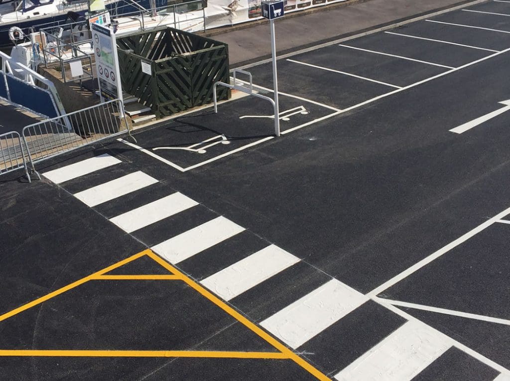 Freshly painted car park markings in Bournemouth, showcasing clear white lines, a pedestrian crossing, and safety indicators for organized parking and traffic flow.
