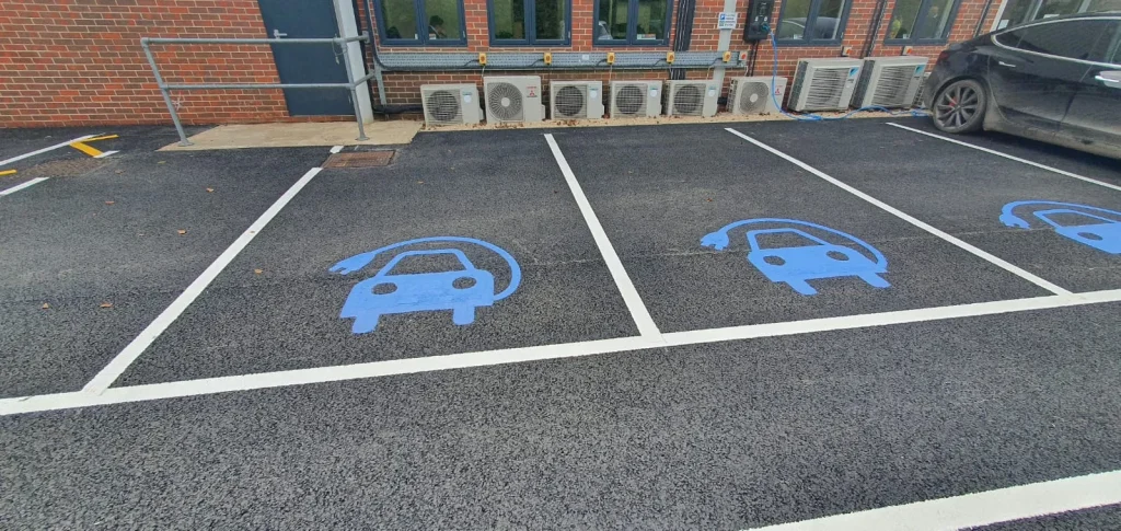 Designated electric vehicle parking bays with blue car symbols and clear white line markings, ensuring organized and accessible charging spots.