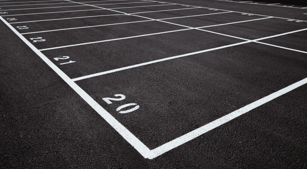 Black-and-white view of a parking lot with freshly painted white numbered lines, clearly designating individual parking spaces.