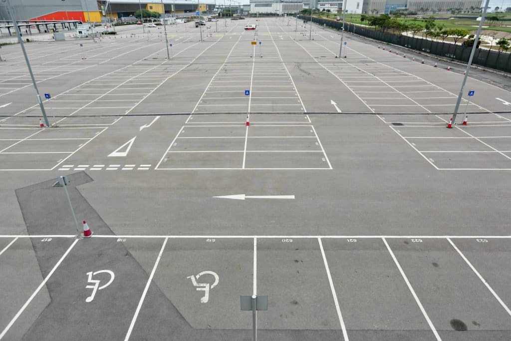 Large empty car park with freshly painted white line markings, directional arrows, and designated accessible parking spaces for organized vehicle arrangement.