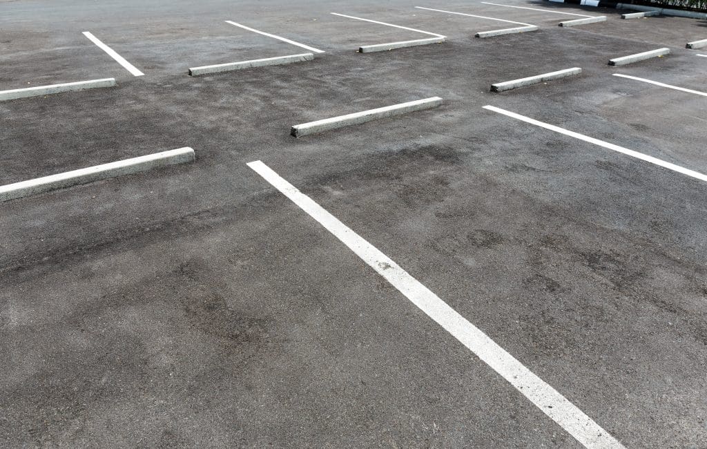 Empty parking lot with freshly painted white lines and barriers, providing clear and organized parking spaces.