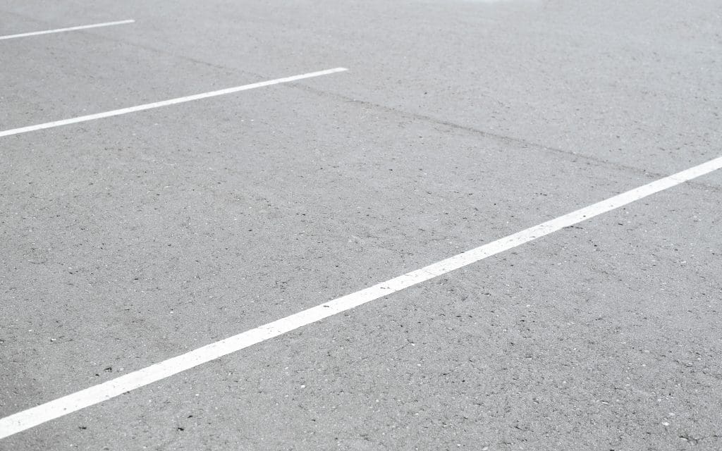 Close-up view of clean white parking lines on an empty asphalt surface, clearly marking organized parking spaces.