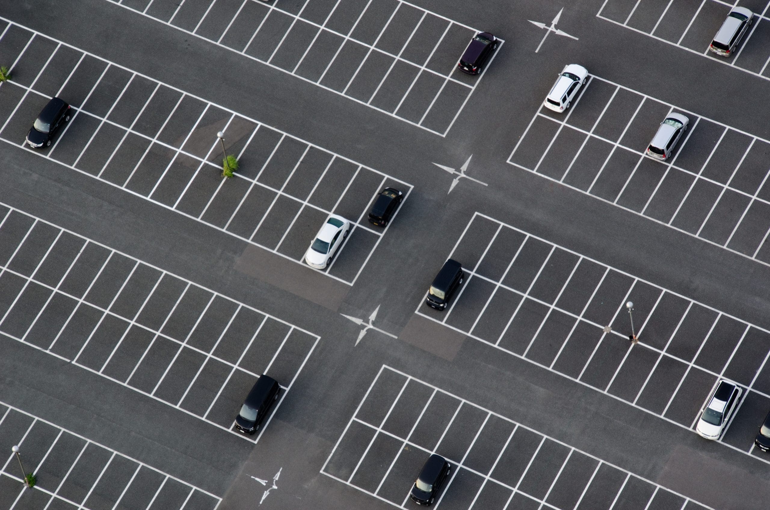Aerial view of a car park with clean, professionally marked white parking lines and directional arrows for efficient vehicle organization.